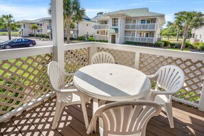 Enjoy a balcony with a table and chairs, overlooking a residential complex with beautifully maintained grounds.