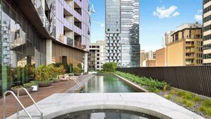 Un immeuble moderne doté d’une piscine, entouré d’autres immeubles de grande hauteur.