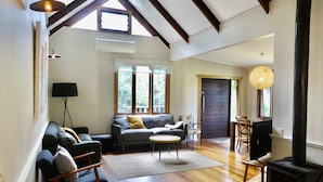 A spacious living room with a sofa, a round coffee table, and a fireplace. - Mansfield on the Manning (Tinonee)