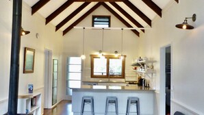 A spacious kitchen with a high ceiling, wooden beams, and a central island with stools. - Mansfield on the Manning (Tinonee)