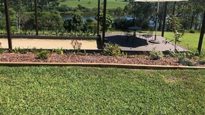 A deck with outdoor seating and a view of a lake and hills. - Mansfield on the Manning (Tinonee)