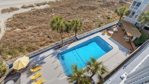 A rooftop pool with lounge chairs and a view of the beach.