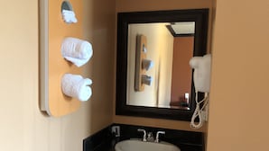 A bathroom with a sink, mirror, and three towels hanging on a rack. - El Rancho Motel (Los Angeles)
