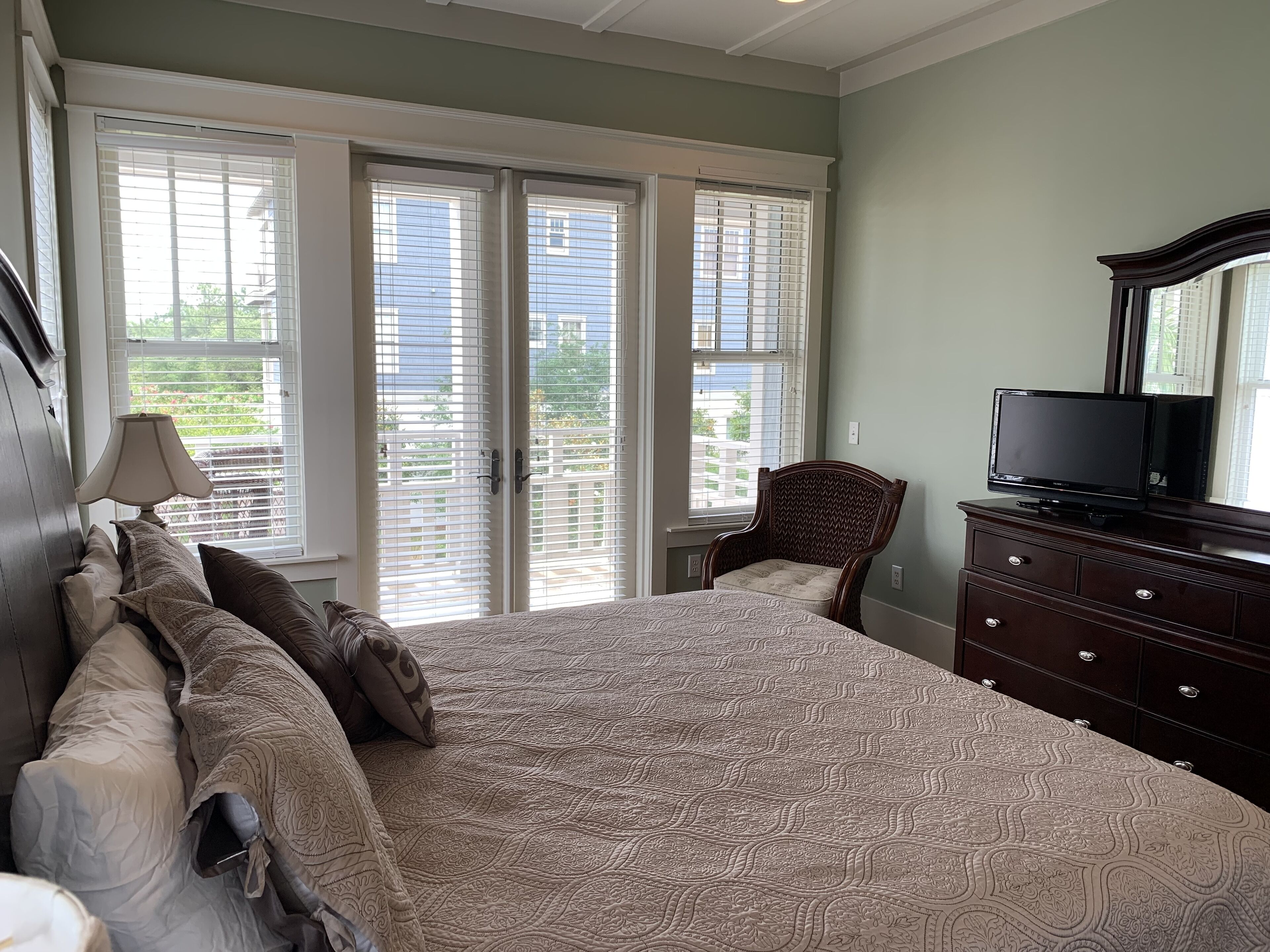 A bedroom with a large bed, a dresser, a chair, and a TV.