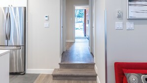 A modern kitchen with a stainless steel refrigerator, a wooden staircase leading to a door, and a red couch with patterned cushions. - Painted Cliff 18  Ski-in, Ski-out Luxury with serene mountain view, sleeps 7 (Whistler)