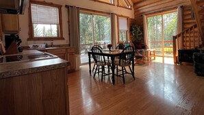 A spacious kitchen with a large island, wooden flooring, and large windows offering views of the outdoors. - 1 BR+ Loft, Log Cabin With Lakeview, Sleeps 4, 5 mins to Glacier (West Glacier)