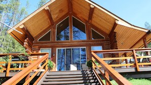 A wooden cabin with a steeply pitched roof, large windows, and a staircase leading to the entrance. - 1 BR+ Loft, Log Cabin With Lakeview, Sleeps 4, 5 mins to Glacier (West Glacier)