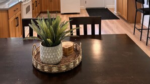 A modern kitchen with wooden cabinets, a white refrigerator, a microwave, and a dining area with a table and chairs. - Town & Country Cottage. Located in the heart of Intercourse, Pa. (Ronks)