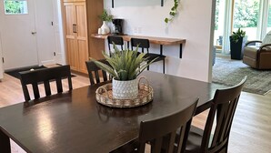A dining area with a dark wooden table, four chairs, a potted plant, and a coffee station. - Town & Country Cottage. Located in the heart of Intercourse, Pa. (Ronks)