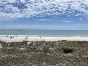 A beach with people, a blue umbrella, and a clear sky. - Sea Cloisters II Ocean Front Beach Retreat (North Myrtle Beach)