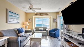 A living room with a sofa, armchair, coffee table, and TV stand. - Sea Cloisters II Ocean Front Beach Retreat (North Myrtle Beach)