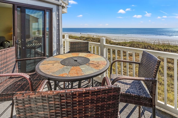 A balcony with wicker furniture and a glass door leading to a room.