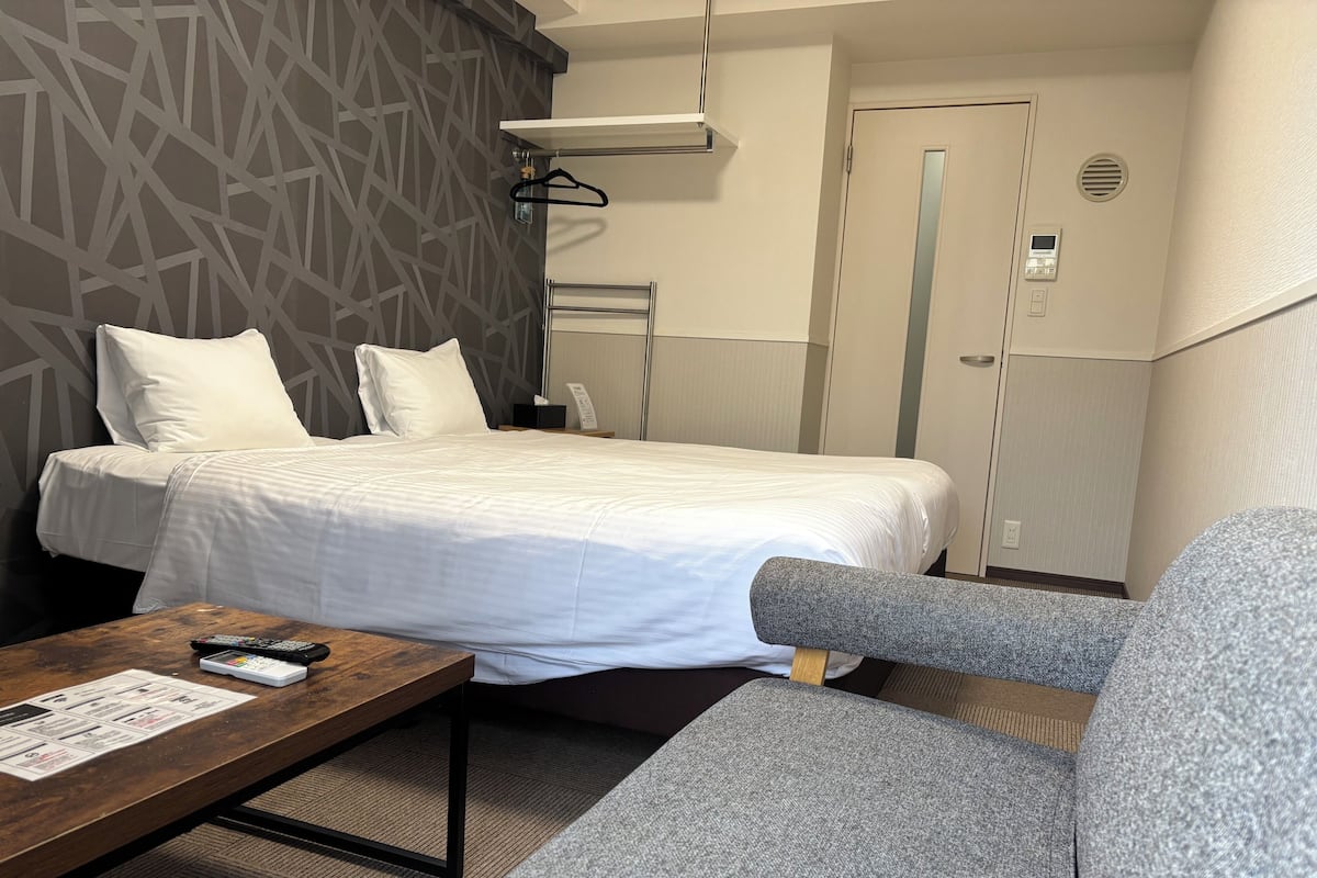 Ein Hotelzimmer mit einem Bett, einer Couch, einem Holztisch und einer Wand mit geometrischem Muster.