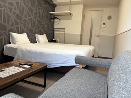 Una habitación de hotel con una cama, un sofá, una mesa de madera y una pared con diseño geométrico.