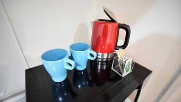 Een zwarte tafel met drie blauwe kopjes en een zwart-rode koffiezetapparaat.
