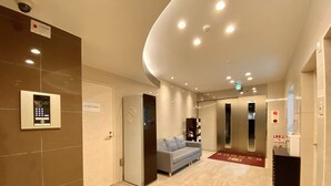 Een moderne lobby met een receptiebalie, een deur voor personeel, een bank en een lift.
