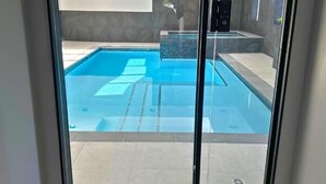 A modern glass door leading to a swimming pool area with a clear view of the pool and surrounding architecture. - Indoor Pool & Hot Tub, Steps to Ski Lift (Blue Mountains)