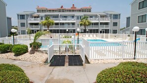 A hotel with a pool area, white fences, and a multi-story building with balconies. - Sea Cloisters II Ocean Front Beach Retreat (North Myrtle Beach)