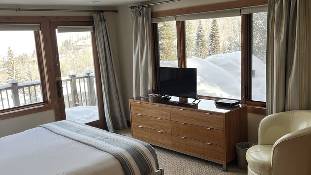 A bedroom with a bed, a wooden dresser, a TV, and a chair. - Beautiful 6BR house on Snowmass mountain w easy access to ski in and out (Snowmass Village)