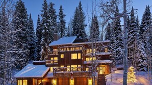 Ein mehrstöckiges Holzhaus mit mehreren Balkonen vor einer verschneiten Landschaft.