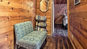 A cozy room with wooden walls, a patterned sofa, and a bookshelf. - Cozy Home w/ Patio Near Yosemite National Park! (Mariposa)