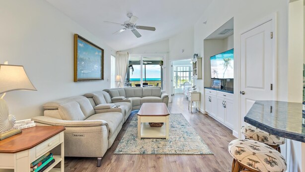 A spacious living room with a large sectional sofa, a coffee table, and a view of the ocean through large windows.