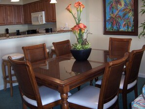 Un comedor con una mesa de vidrio rodeada de sillas de madera con asientos acolchados.