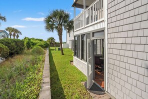 A two-story house with a balcony, a well-maintained lawn, and a palm tree.