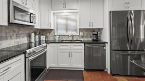A modern kitchen with white cabinets, stainless steel appliances, and a tiled backsplash. - Sea Cloisters II Ocean Front Beach Retreat (North Myrtle Beach)