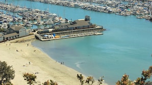 A marina with boats docked, a beach with people, and a building with a dock. - Dana Point Dream Home with White Water Ocean View (Permit #STR14-0084) (Dana Point)
