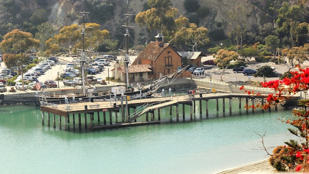 A pier extending into a body of water with a building and parked cars nearby. - Dana Point Dream Home with White Water Ocean View (Permit #STR14-0084) (Dana Point)