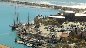 A harbor with a large sailing ship docked, a parking lot, and a building with a red roof. - Dana Point Dream Home with White Water Ocean View (Permit #STR14-0084) (Dana Point)