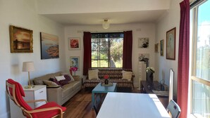 Un salon avec un canapé, un fauteuil rouge, une table et un téléviseur.