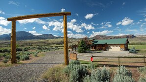 Eine Lodge mit grüner Dachbegrünung, einem Schotterweg und einem hölzernen Bogenportal.