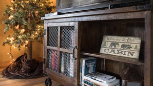 Eine Holz-Unterhaltungsanlage mit Fernseher, Büchern und einem Schild, auf dem 'Willkommen in unserer Hütte' steht.
