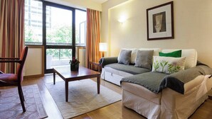 Una sala de estar con sofá, sillón, mesa de centro y ventana con cortinas.