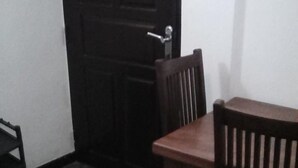 A room with a wooden table and chairs, a dark door, and a patterned carpet. - Ashley Hills (Nuwara Eliya)