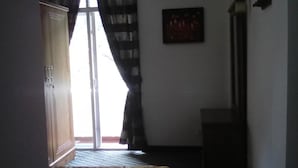 A bedroom with a bed, a wardrobe, a window with curtains, and a wall-mounted light fixture. - Ashley Hills (Nuwara Eliya)