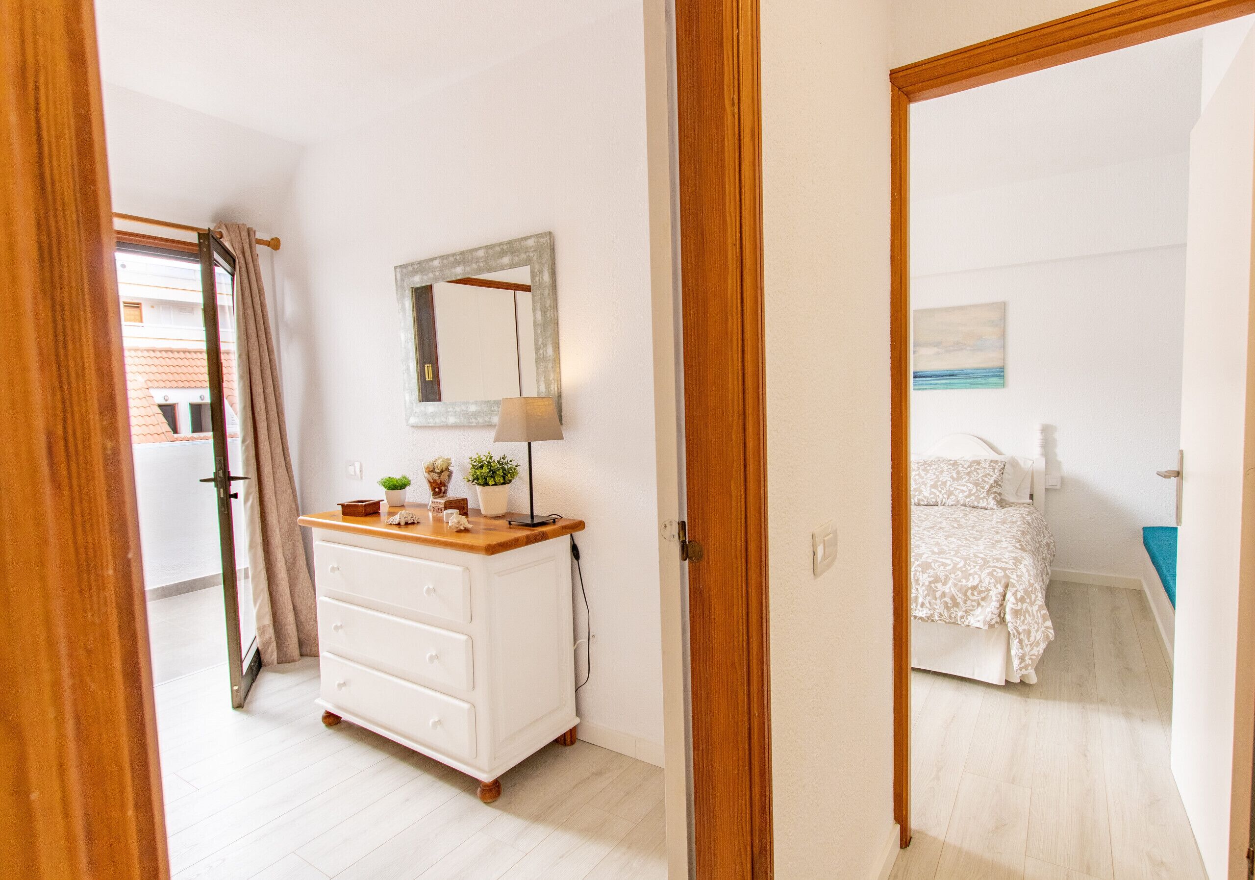 Un dormitorio con cama, cómoda, espejo y ventana con cortinas.