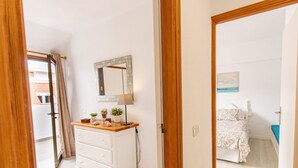 Un dormitorio con cama, cómoda, espejo y ventana con cortinas.
