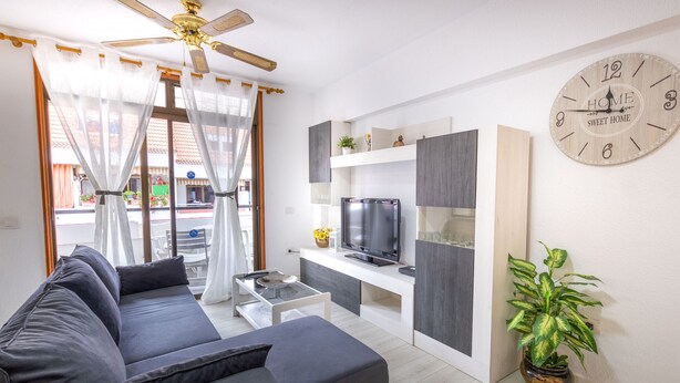 Una sala de estar moderna con un sofá, televisión y un reloj en la pared.