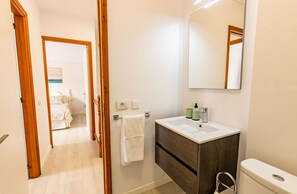 A bathroom with a white sink, dark wooden vanity, and a mirror. There is a towel hanging on the wall and a toilet visible. - Altemar 2A004 totally refurbished (Playa de Las Americas)