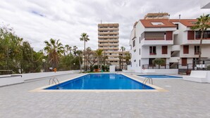 Zona de piscina con vista a un edificio de varios pisos al fondo.