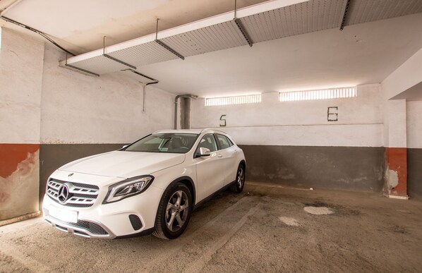 A white car parked in a multi-level parking garage with visible structural elements and numbered parking spaces. - Altemar 2A004 totally refurbished (Playa de Las Americas)