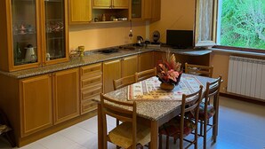 A kitchen with wooden cabinets, a granite countertop, and a dining table with chairs. - Secluded house in the mountains with garden (Pergola)
