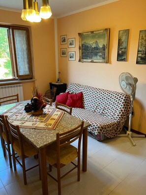 Un accogliente soggiorno con tavolo da pranzo, sedie, divano e una ventola.