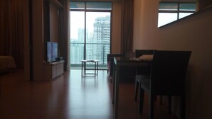 Een hotelkamer met een groot raam, een televisie, een eettafel en een stoel.