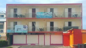 Un edificio de dos pisos con un letrero que dice 'Hotel Le Cap Vert' y un letrero de 'WORLD SHOP' debajo.
