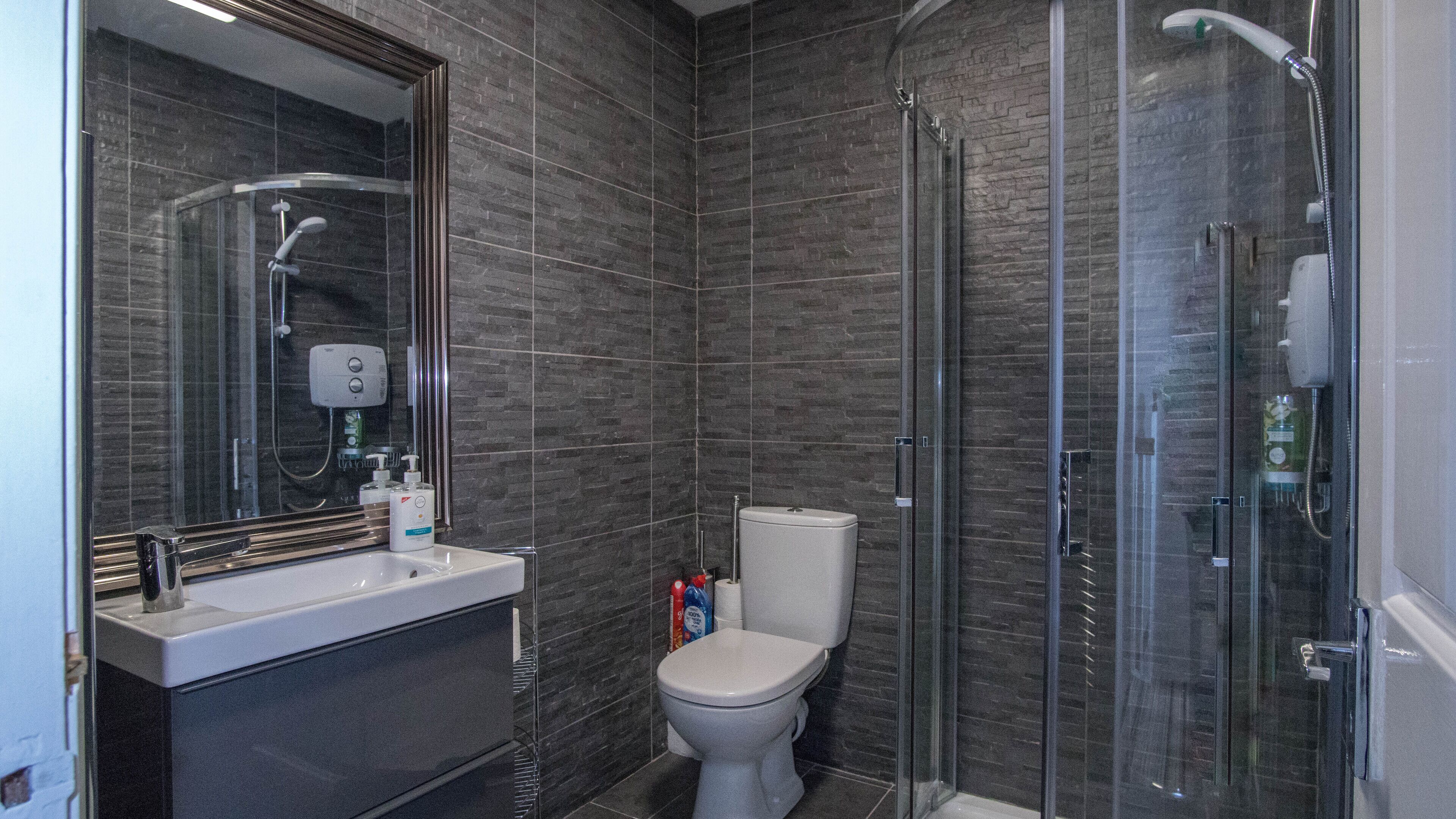 A modern bathroom with a glass shower enclosure, a white sink, and a toilet.