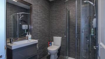 A modern bathroom with a glass shower enclosure, a white sink, and a toilet.